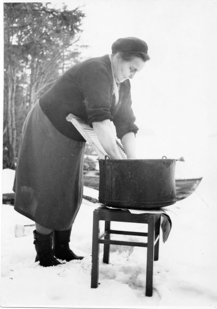 En kvinna tvättar kläder i en balja.