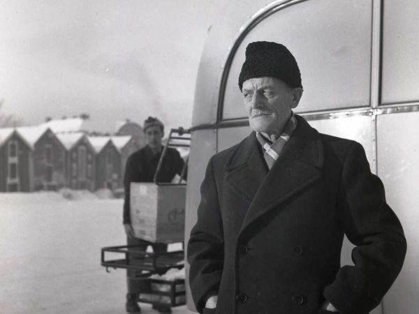 En man står framför en buss med händerna i rockfickorna.
